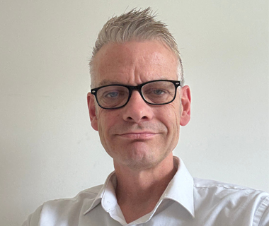 Mark Cavill in a white shirt wearing glasses