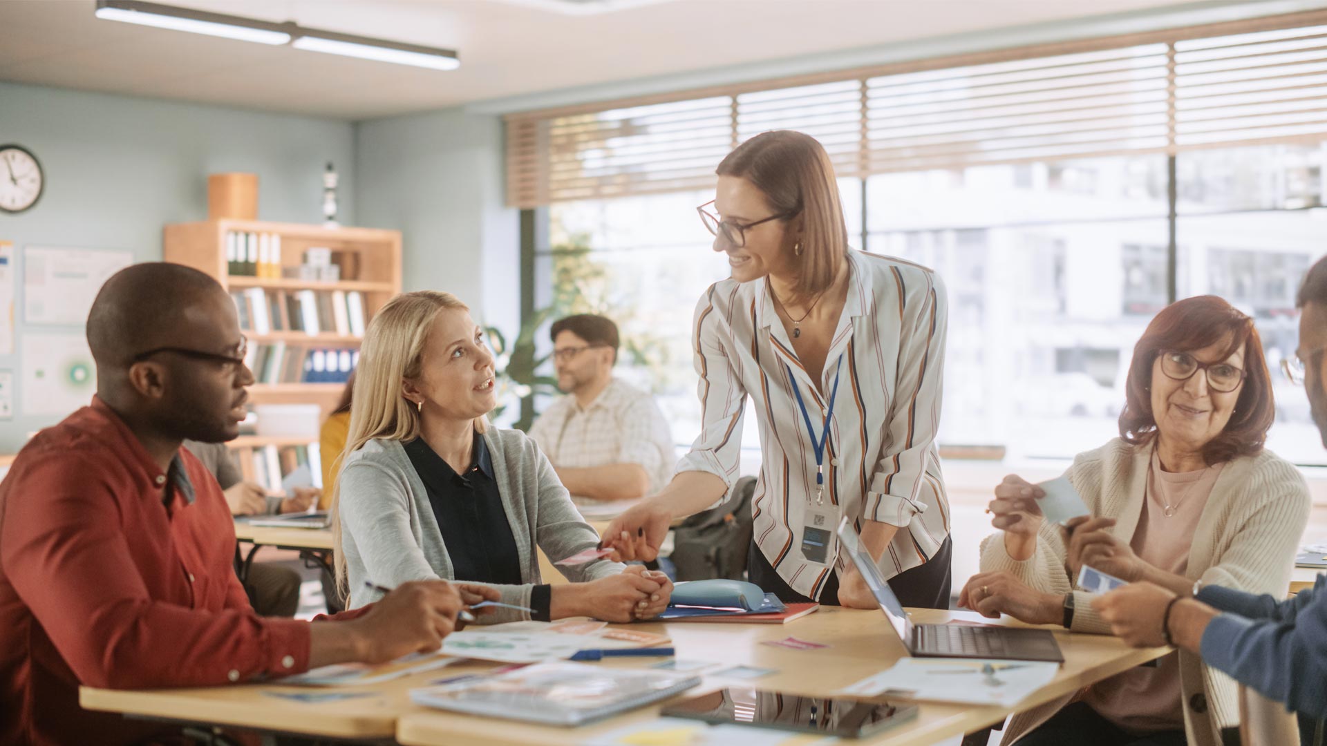 Adults sat around a large table, learning in a classroom environment 