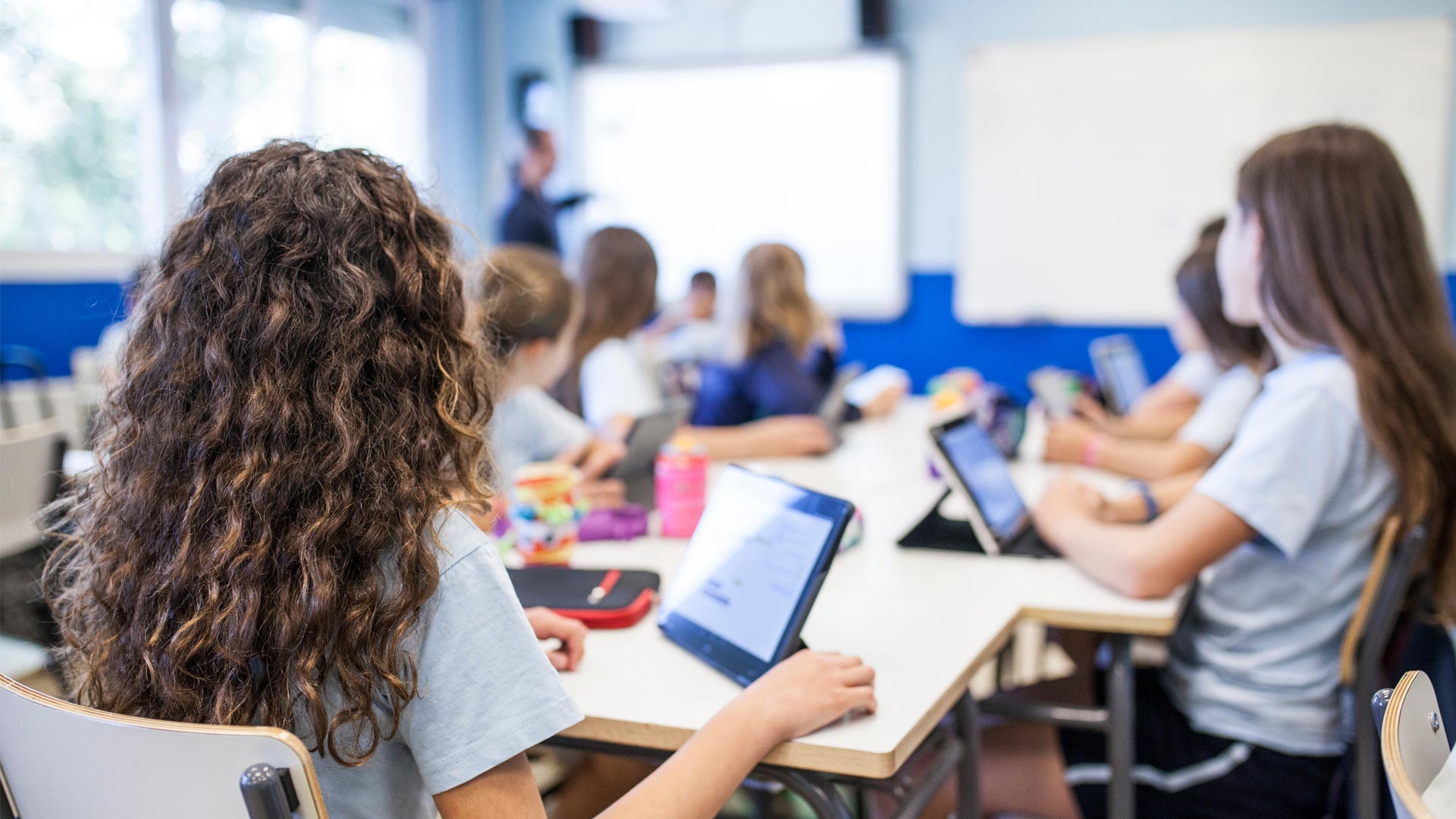 Secondary school students studying in class with tablets propped up on the tables in front of them