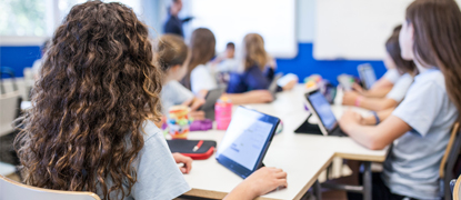 Secondary school students studying in class with tablets propped up on the tables in front of them