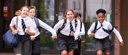 A group of schoolchildren running and laughing together in a school playground