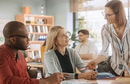 Adults sat around a large table, learning in a classroom environment 