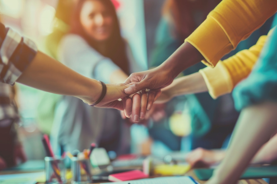 Teachers with their hands on top of each other above a classroom table of paints