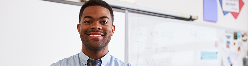 Teacher stood in front of whiteboards smiling.