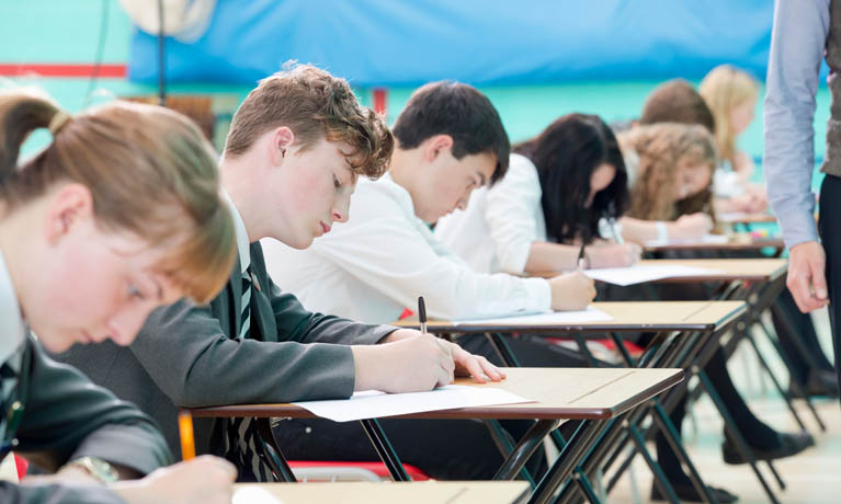 School pupils sat at exam desks during test.