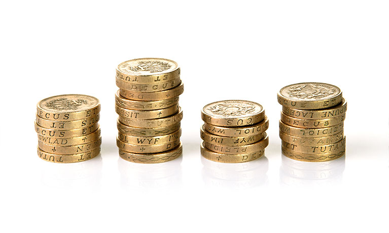 Four varied piles of pound coins on white table