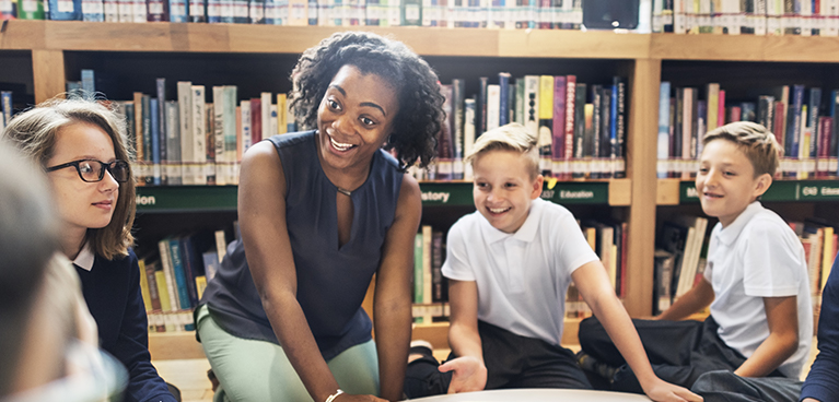 teacher sitting with her students in a library.