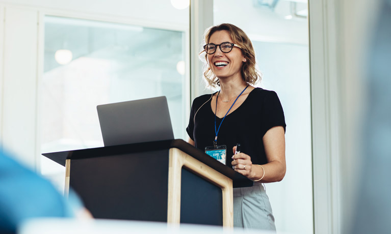 Female stood at the front of a room presenting