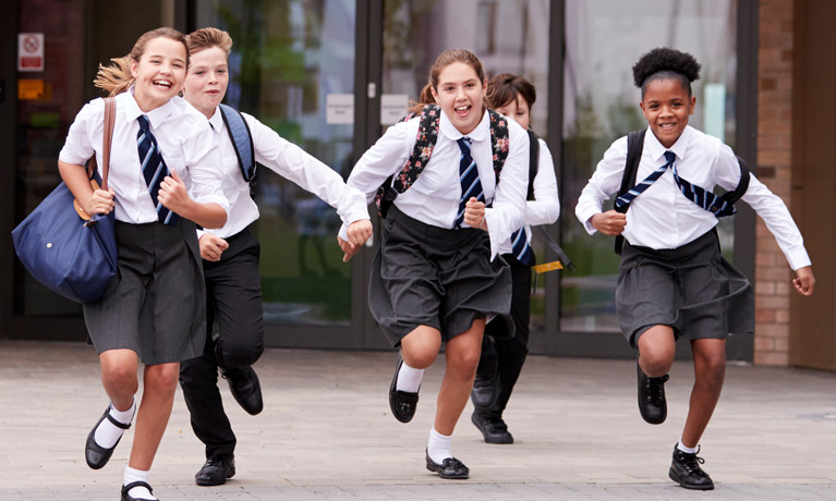 A group of secondary schoolchildren running and laughing.
