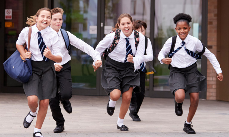 Schoolchildren running in a group in school uniform.