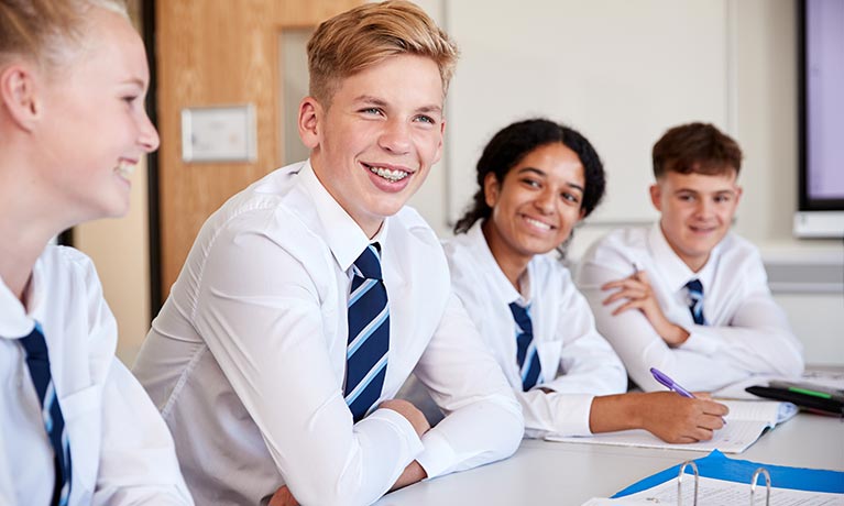 Group of pupils sat at desk in classroom.