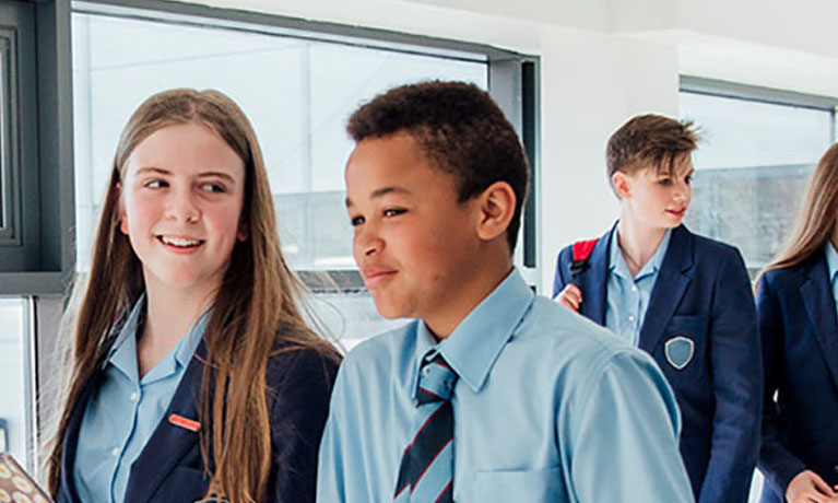 A male and female pupil walking in corridor.