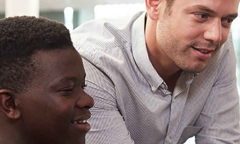Male teacher looking at screen with pupil