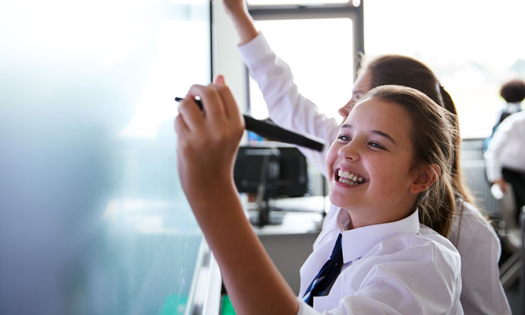 girl drawing on white board in classroom.