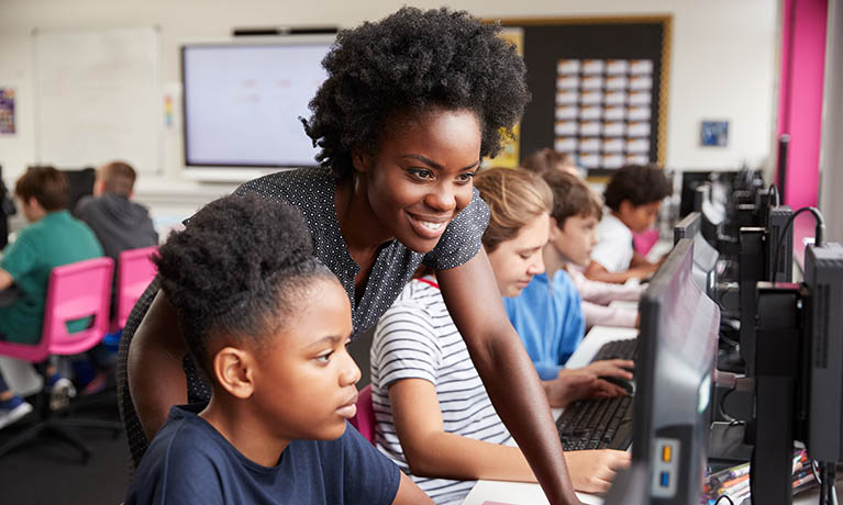 Teacher looking at pupils computer in classroom.