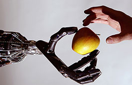 Robot hand holding apple, human hand reaching to take it