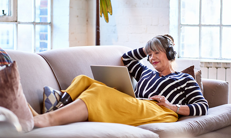 Woman with a prosthetic leg sitting on a sofa with a headset studying online