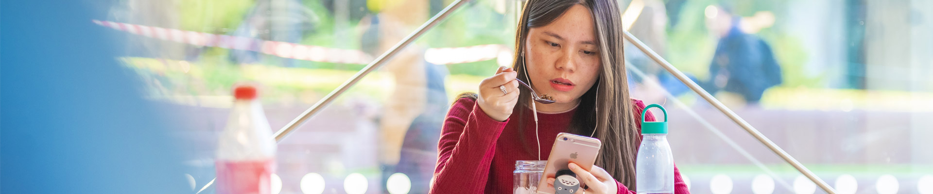 A student looking at her phone in a cafe on campus.