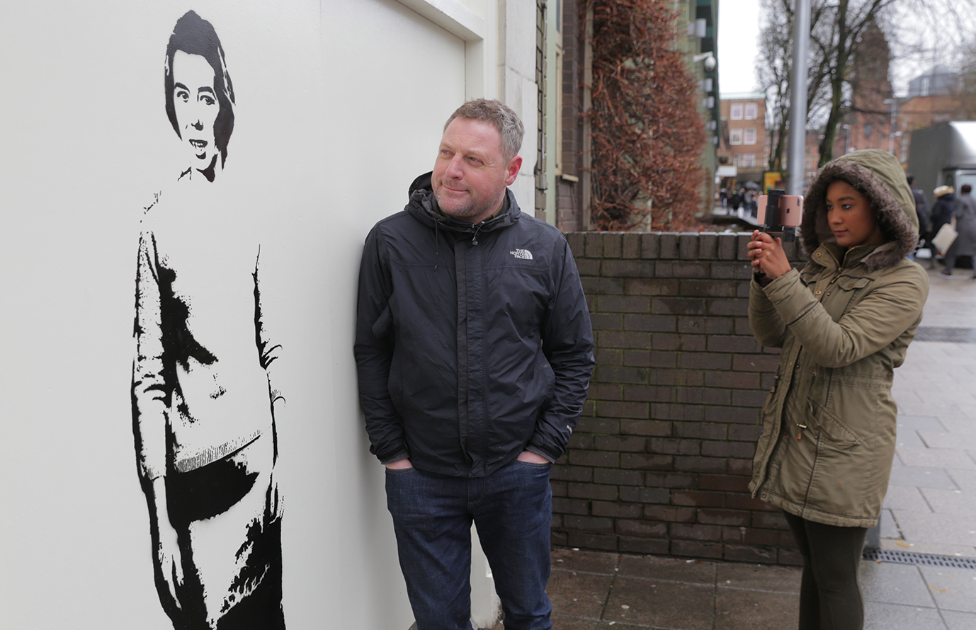 Graffiti artist, Stewy, posing next to his latest portrait of Delia Derbyshire, located outside the Ellen Terry building on campus.