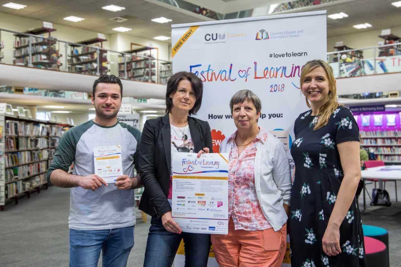 Four people stood in a library in front of a poster