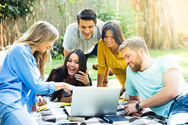 students-smiling-looking-at-laptop-in-park