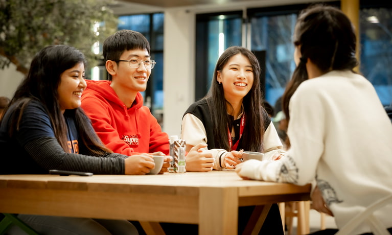 Group of students sat at a table smiling