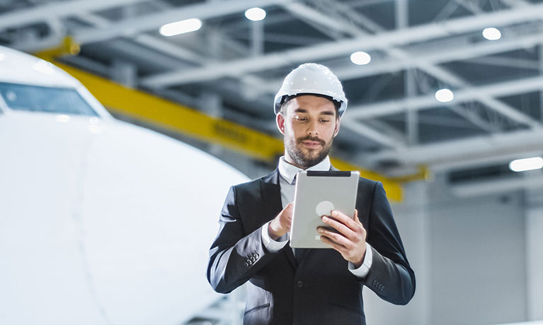 Man wearing a safety hat writing on a notepad