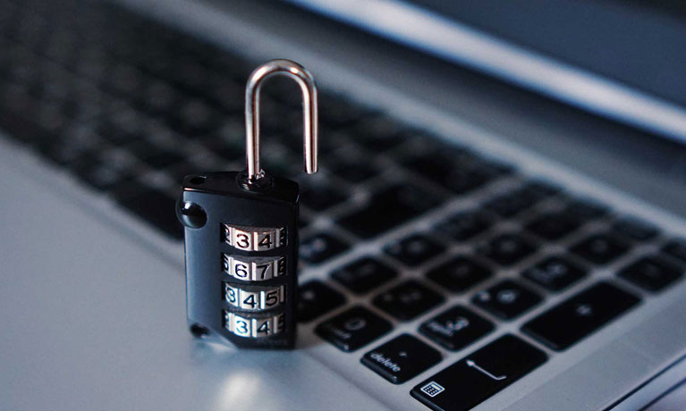 A four dial padlock, unlocked, next to a keyboard