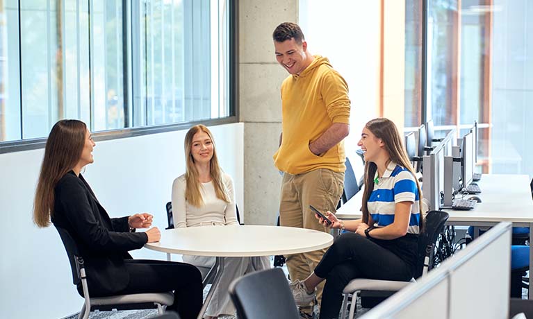 Four students laughing and smiling.