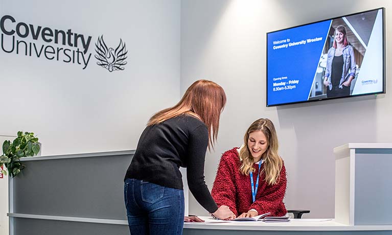 Two staff members talking at a help desk