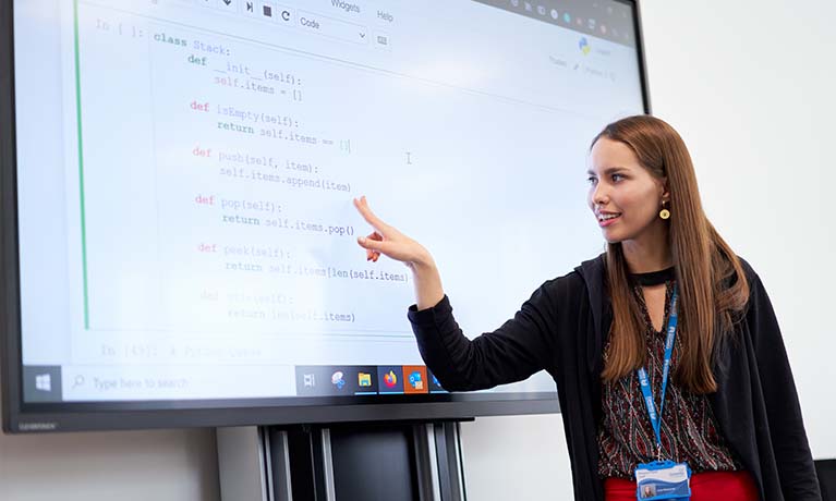 Teacher pointing at a digital whiteboard.