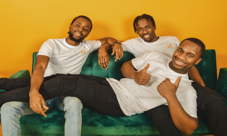 Three young men sat together on sofa.