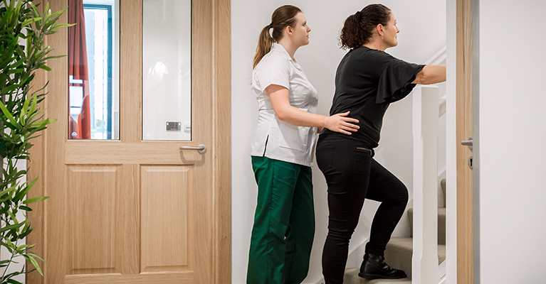 Student in uniform aiding a patient upstairs