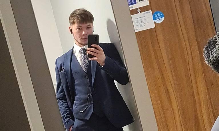 Olly a student taking a photo of himself in a suit