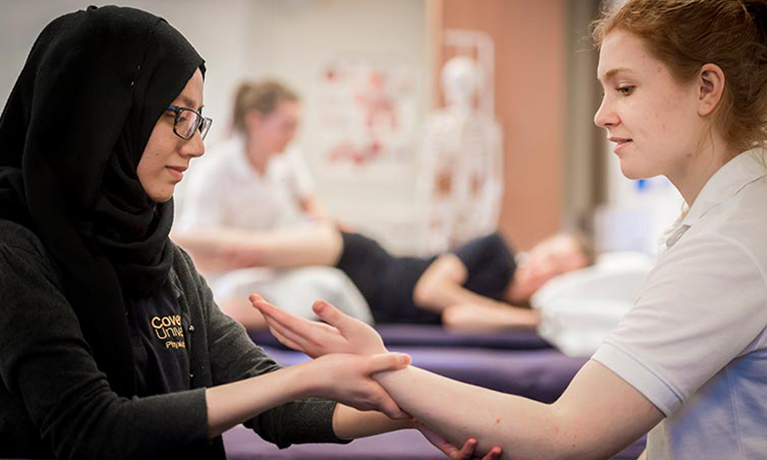 A student practicing physiotherapy on a students arm