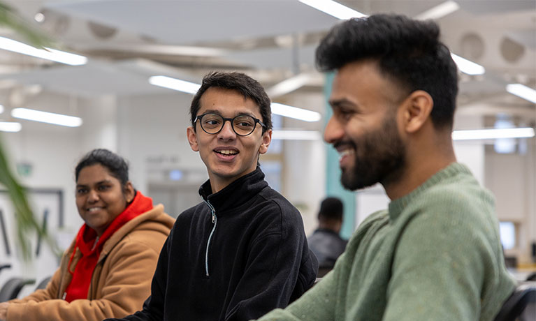 three students sitting togther in a library social space