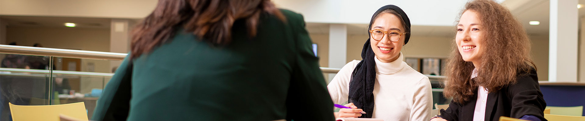 3 students sitting at a desk in a social space