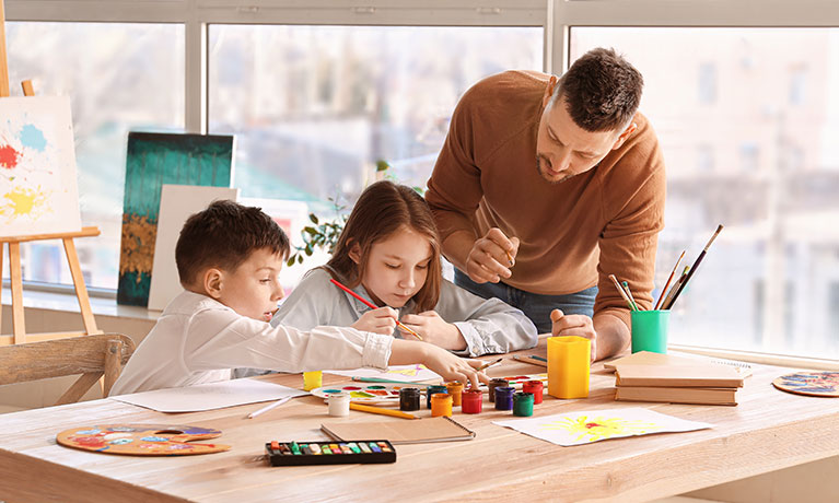 Male teacher helping young students in a classroom
